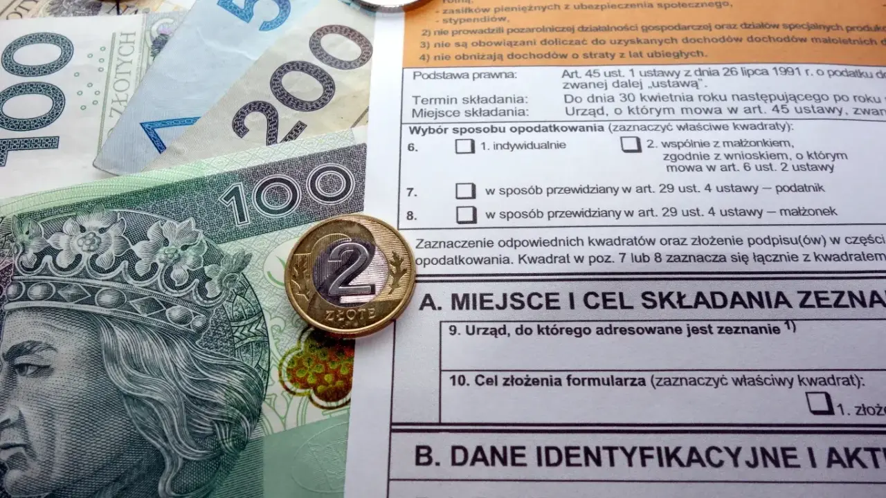 Polskie banknoty i monety na tle formularza podatkowego, ilustrujące ulga termomodernizacyjna – przykład rozliczenia.