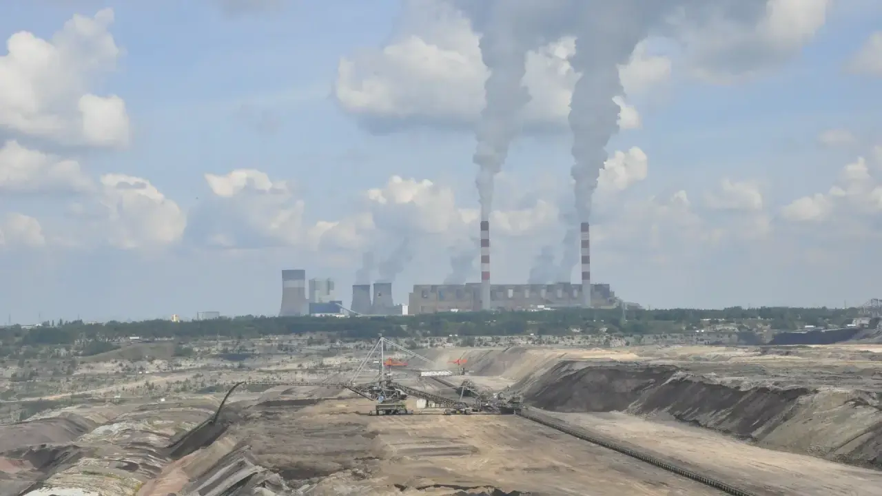 Widok na kopalnię odkrywkową i elektrownię Bełchatów z dymiącymi kominami.