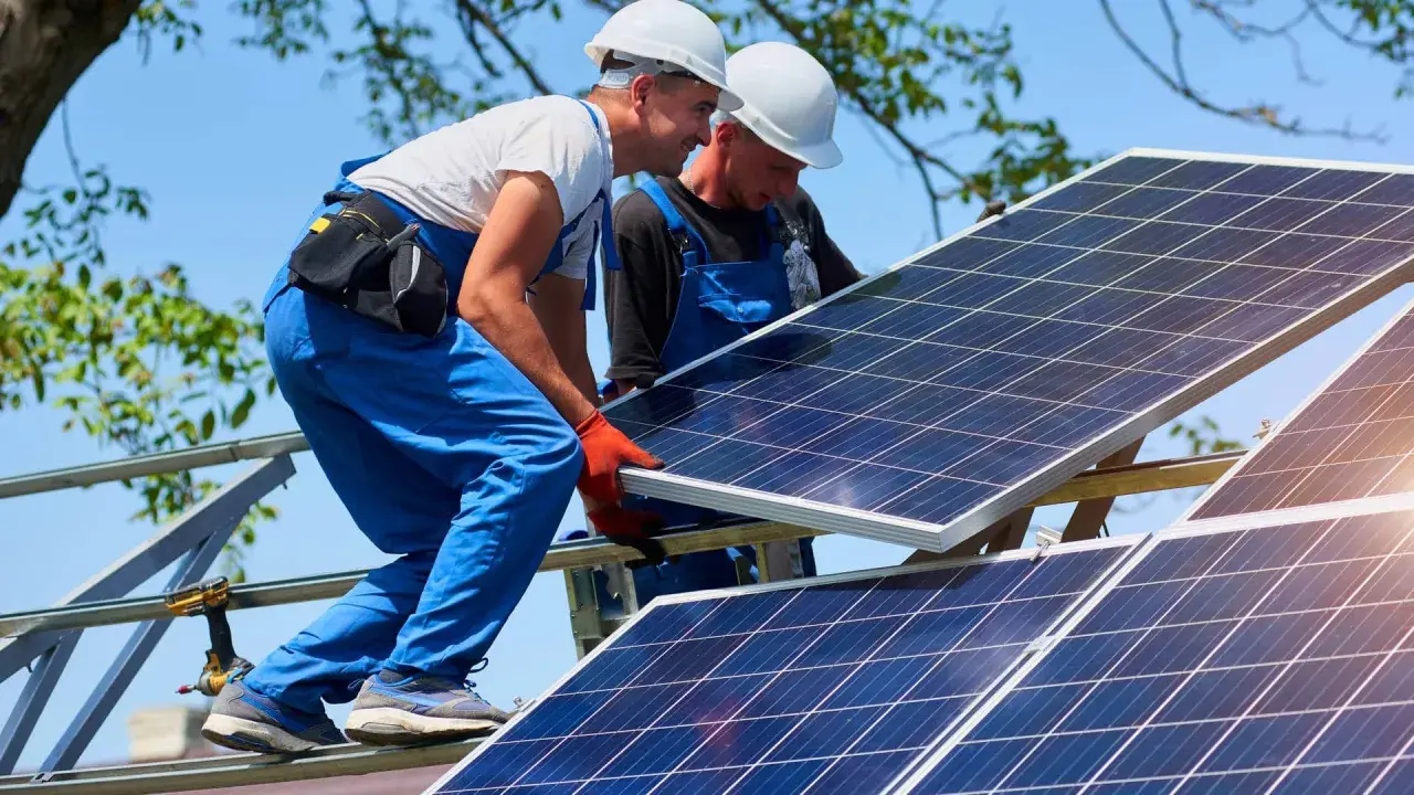Dwóch monterów instaluje panele fotowoltaiczne. Zastanawiasz się, ile to kw? 10 kwp to moc szczytowa instalacji.