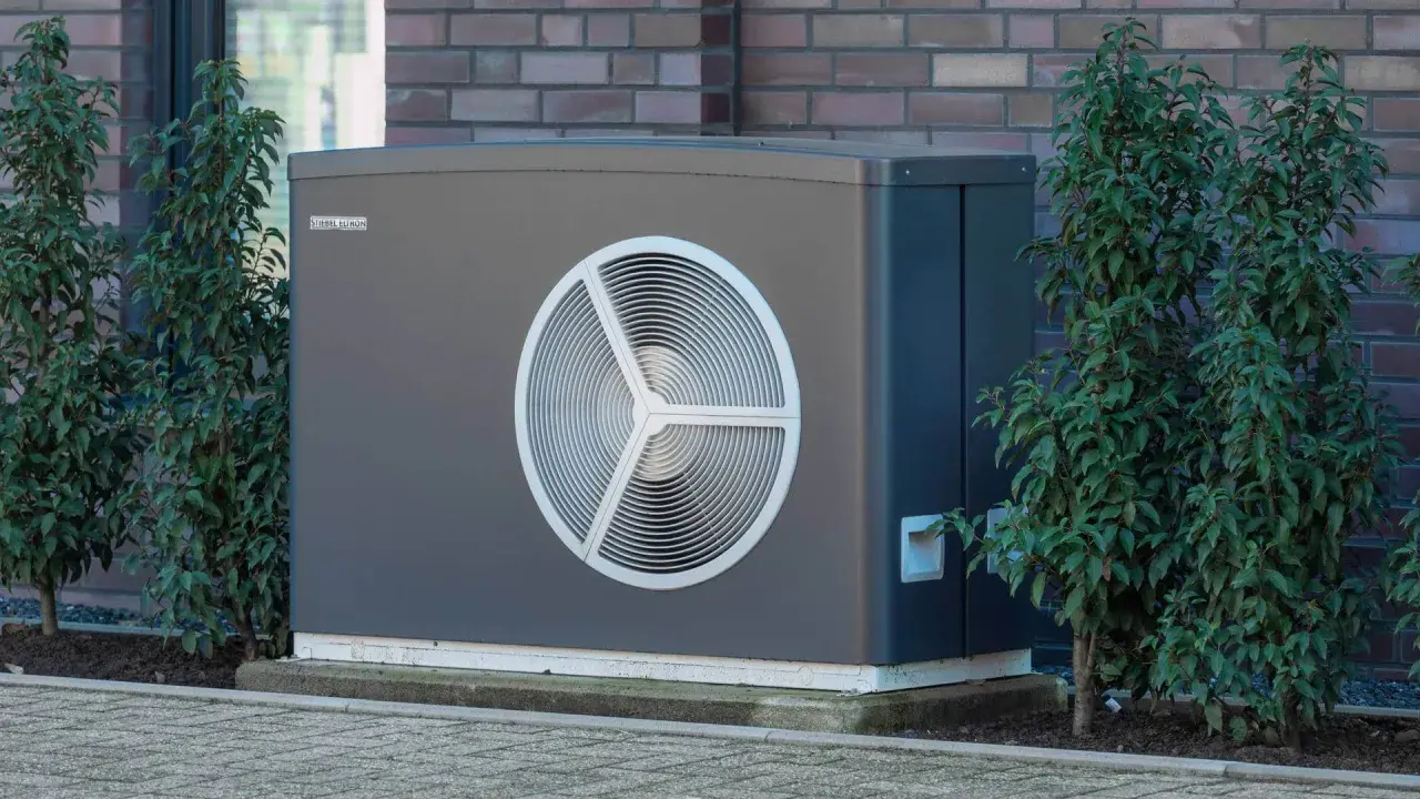 Nowoczesna pompa ciepła STIEBEL ELTRON. Jaka moc pompy ciepła do domu 200m2? Urządzenie stoi obok zielonych krzewów.