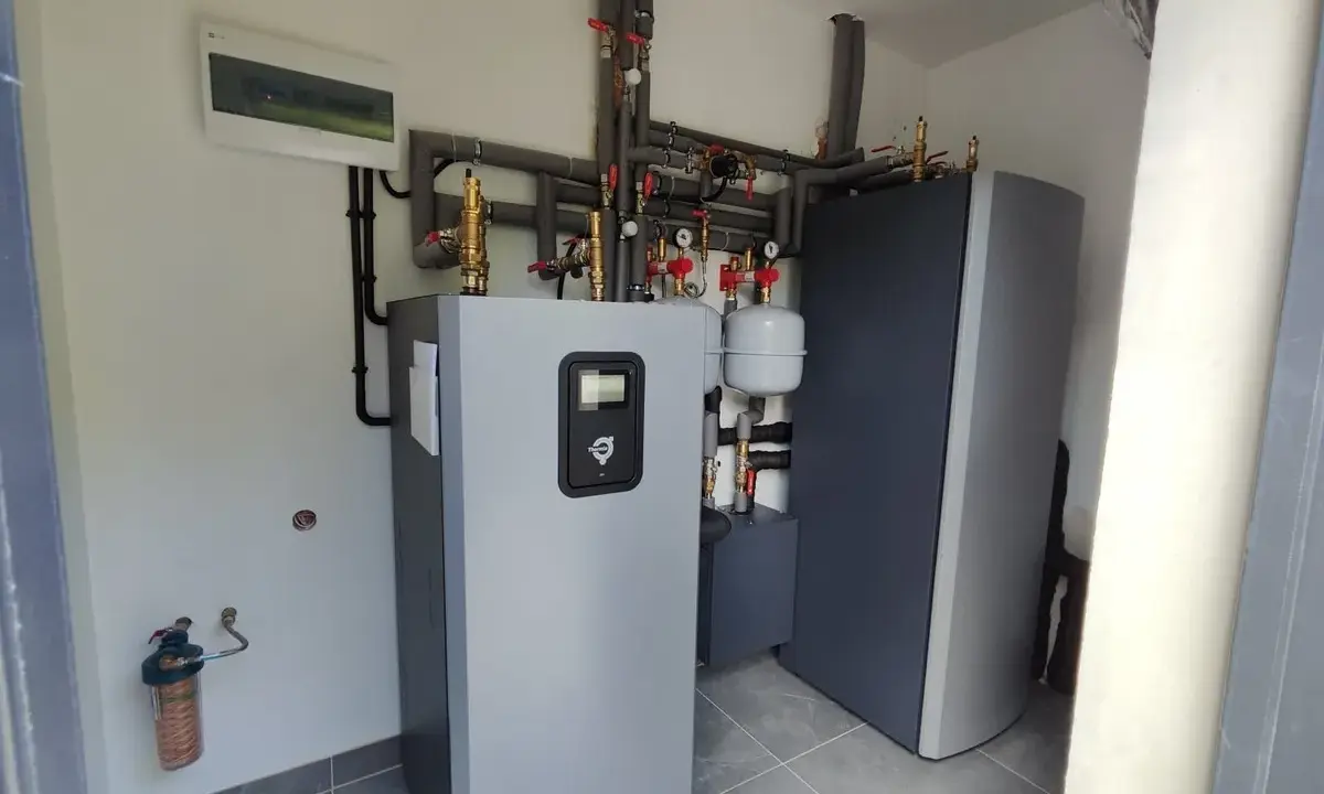 Profesjonalny montaż pompy ciepła. Widoczny zbiornik, instalacja hydrauliczna i rozdzielnica elektryczna.