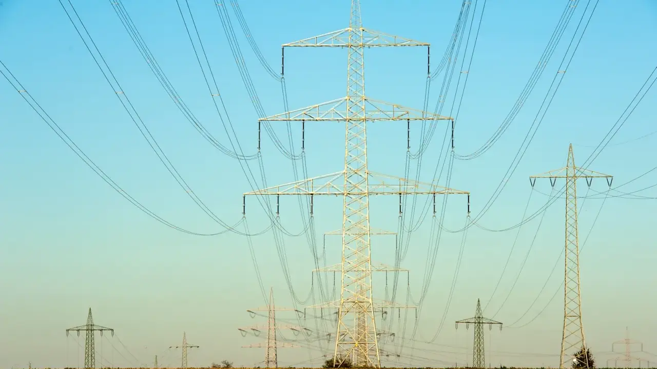Linie energetyczne przecinają błękitne niebo. Czy ta sieć przesyłowa 1MW ile to kw zasila okoliczne pola?