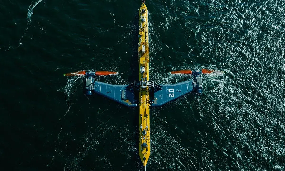 Podwodna turbina wykorzystująca energię pływów, z charakterystycznymi żółto-niebieskimi elementami i pomarańczowymi śmigłami, zanurzona w ciemnych wodach oceanu.