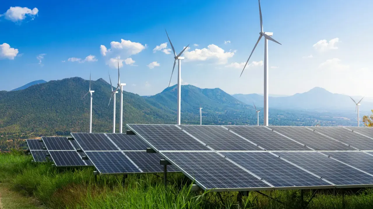 Panele słoneczne i wiatraki na tle gór i błękitnego nieba. To przyszłość, którą wspiera program Energia Plus.