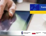 Dłoń dotyka ekranu tabletu, szukając informacji o pożyczki unijne. Na ekranie widnieje napis "Fundusze Europejskie".