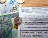 Polskie banknoty i monety na tle formularza podatkowego, ilustrujące ulga termomodernizacyjna – przykład rozliczenia.