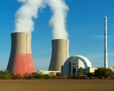 Dwie chłodnie kominowe i kopuła elektrowni konwencjonalnej na tle błękitnego nieba.