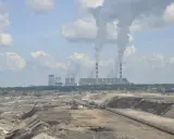 Widok na kopalnię odkrywkową i elektrownię Bełchatów z dymiącymi kominami.