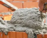 Łopata z zaprawą murarską na cegłach. Czas schnięcia zaprawy murarskiej zależy od wielu czynników.