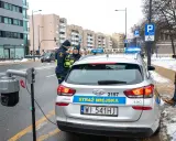 Strażnicy miejscy w Warszawie przy radiowozie i kamerze monitoringu. Dbają o czystą strefę i porządek.
