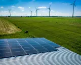 Panele słoneczne na dachu i wiatraki na polu, symbolizujące program agroenergia i zrównoważony rozwój.
