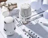 Termostaty grzejnikowe i zawór na tle planów instalacji grzewczej. Optymalizacja średniego zużycia ciepła na m2.