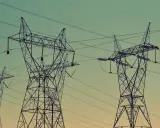 Wysokie wieże energetyczne z liniami wysokiego napięcia na tle nieba.