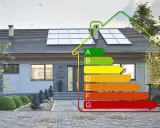 Nowoczesny dom z panelami słonecznymi i etykietą energetyczną. Określa zapotrzebowanie energetyczne domu od A (najlepsze) do G (najgorsze).