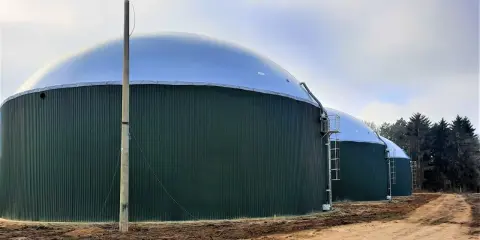 Zielone, cylindryczne zbiorniki z kopułami to biogazownia, gdzie powstaje energia z biomasy.