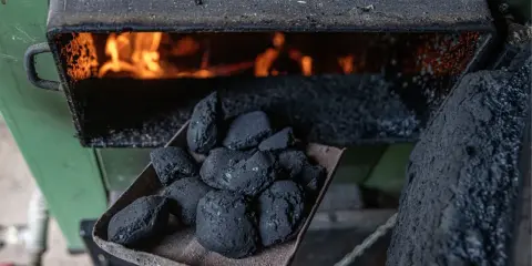 Łopata z węglem brunatnym czeka na załadunek do pieca bezklasowego, gdzie wesoło płonie ogień.