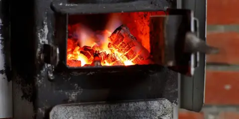 Żarzący się węgiel w starym piecu. Czas pomyśleć, do kiedy trzeba wymienić piec, zanim będzie za późno.