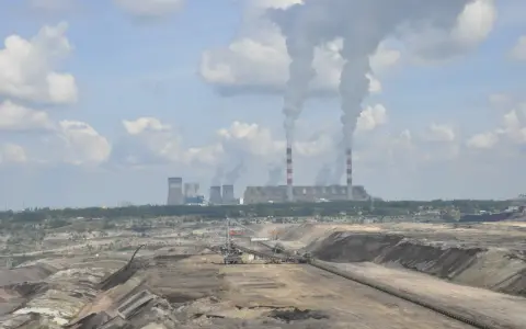 Widok na kopalnię odkrywkową i elektrownię Bełchatów z dymiącymi kominami.