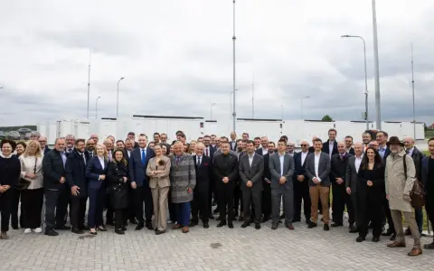 Grupa osób przed bateryjnymi magazynami energii, symbolizującymi rozwój polskiego stowarzyszenia magazynowania energii.