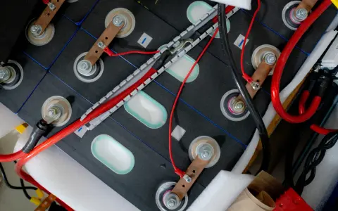 Zestaw ogniw tworzących baterię do samochodu elektrycznego, połączonych miedzianymi listwami i przewodami.