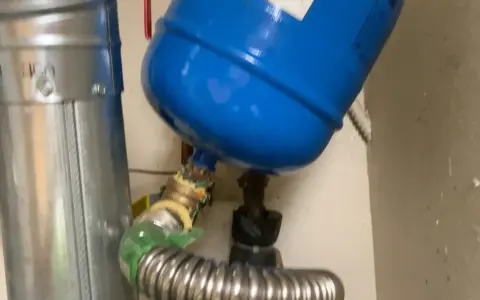 Instrukcja jak odpowietrzyć pompę cyrkulacyjną: widok na niebieski zbiornik i metalowe rury z zaworami.