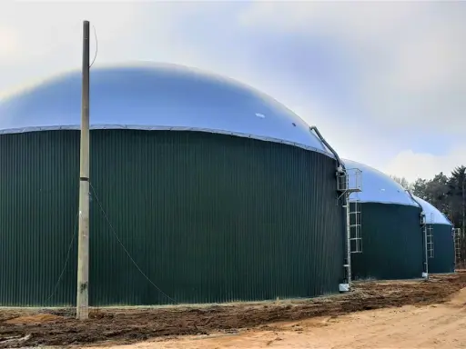 Zielone, cylindryczne zbiorniki z kopułami to biogazownia, gdzie powstaje energia z biomasy.