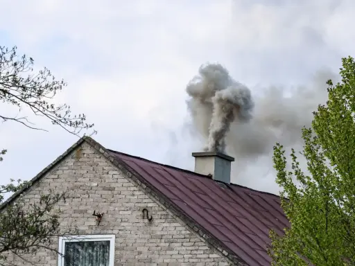 Gęsty dym z komina domu. Kto pobiera opłaty za emisję CO2, gdy takie widoki stają się codziennością?