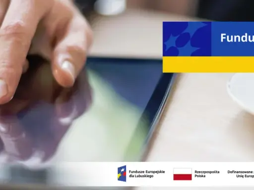 Dłoń dotyka ekranu tabletu, szukając informacji o pożyczki unijne. Na ekranie widnieje napis "Fundusze Europejskie".