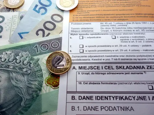 Polskie banknoty i monety na tle formularza podatkowego, ilustrujące ulga termomodernizacyjna – przykład rozliczenia.
