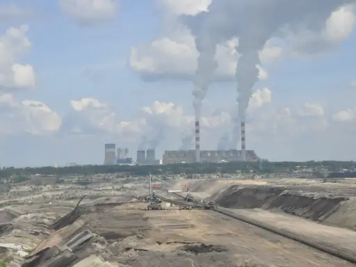 Widok na kopalnię odkrywkową i elektrownię Bełchatów z dymiącymi kominami.