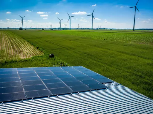 Panele słoneczne na dachu i wiatraki na polu, symbolizujące program agroenergia i zrównoważony rozwój.