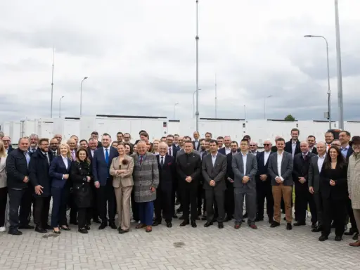 Grupa osób przed bateryjnymi magazynami energii, symbolizującymi rozwój polskiego stowarzyszenia magazynowania energii.