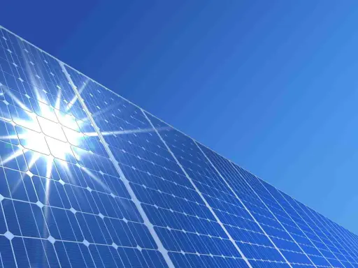 Błyszczące panele słoneczne pod błękitnym niebem. Słońce odbija się od nich, tworząc efektowny blask. To przyszłość energii, a ncbr co to? To Narodowe Centrum Badań i Rozwoju, które wspiera innowacje.