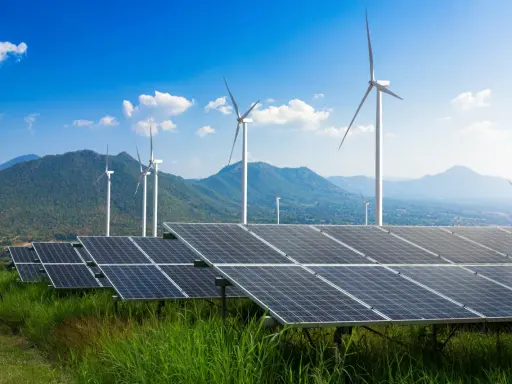 Panele słoneczne i wiatraki na tle gór i błękitnego nieba. To przyszłość, którą wspiera program Energia Plus.