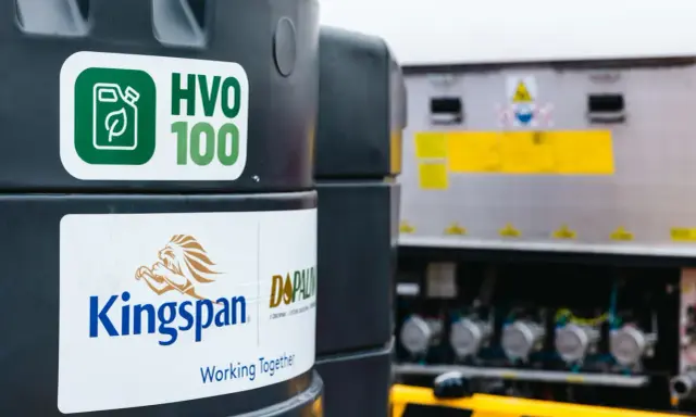 Zbiornik z ekologicznym paliwem HVO 100, obok logo Kingspan. Nowoczesne rozwiązanie dla transportu.