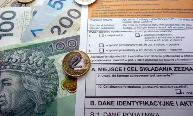 Polskie banknoty i monety na tle formularza podatkowego, ilustrujące ulga termomodernizacyjna – przykład rozliczenia.