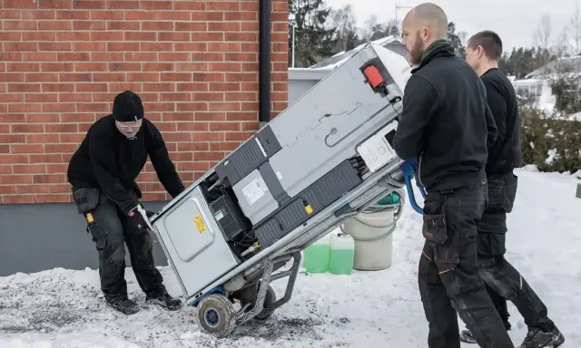Trzech mężczyzn transportuje nowy piec na wózku. Wymiana pieca w zachodniopomorskim może być konieczna przed zimą.