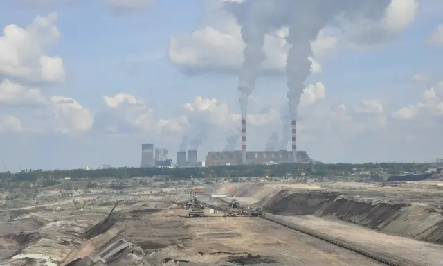 Widok na kopalnię odkrywkową i elektrownię Bełchatów z dymiącymi kominami.