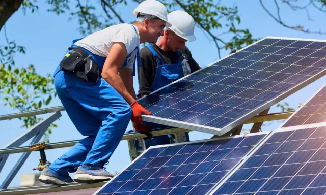 Dwóch monterów instaluje panele fotowoltaiczne. Zastanawiasz się, ile to kw? 10 kwp to moc szczytowa instalacji.