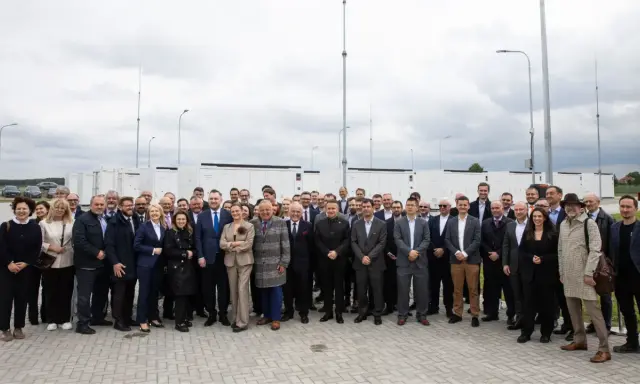 Grupa osób przed bateryjnymi magazynami energii, symbolizującymi rozwój polskiego stowarzyszenia magazynowania energii.