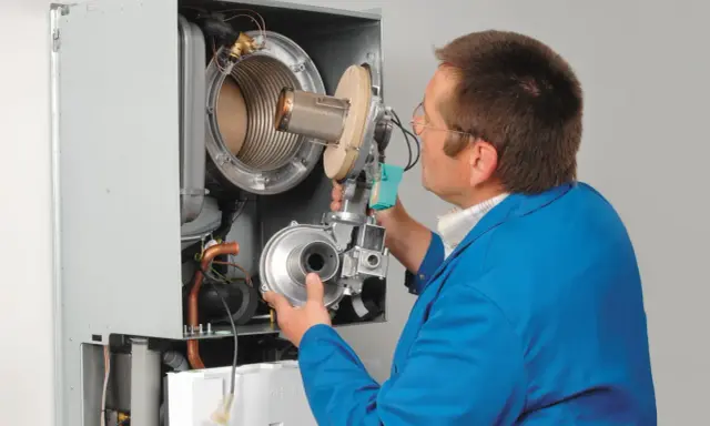 Serwisant sprawdza ciśnienie wody w kotle Viessmann Vitodens 050.