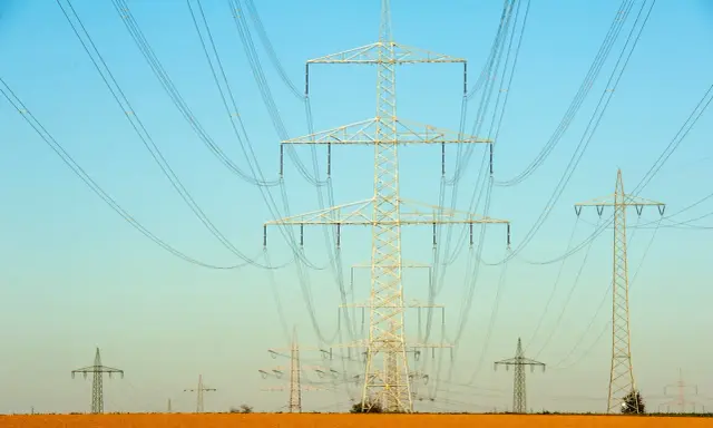 Linie energetyczne przecinają błękitne niebo. Czy ta sieć przesyłowa 1MW ile to kw zasila okoliczne pola?