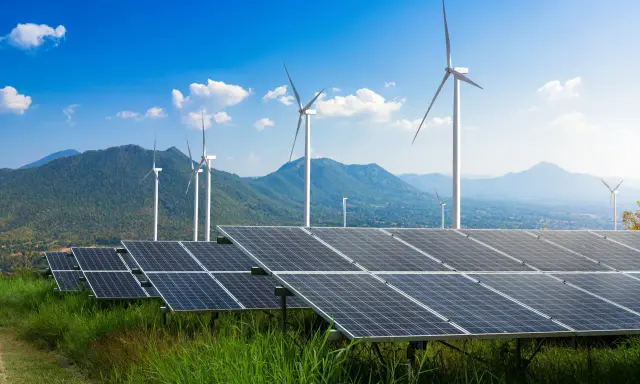 Panele słoneczne i wiatraki na tle gór i błękitnego nieba. To przyszłość, którą wspiera program Energia Plus.