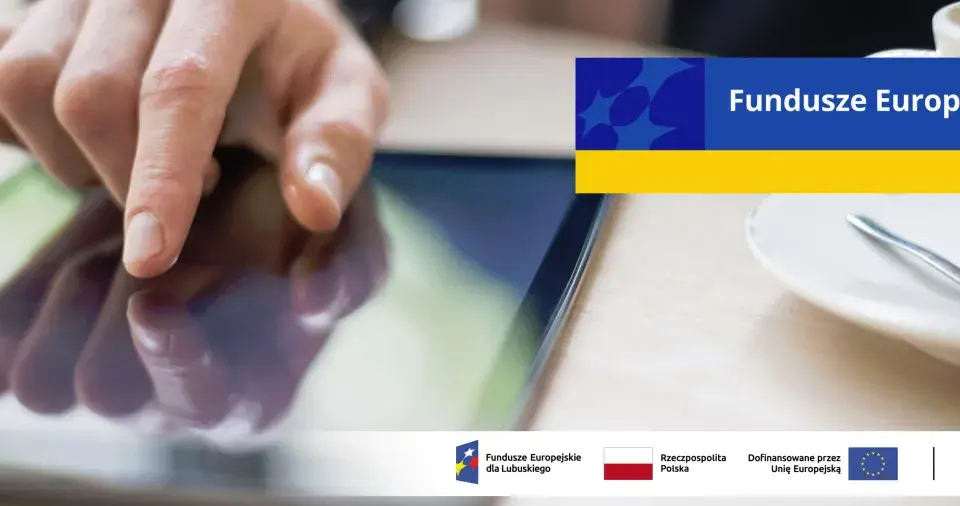 Dłoń dotyka ekranu tabletu, szukając informacji o pożyczki unijne. Na ekranie widnieje napis "Fundusze Europejskie".