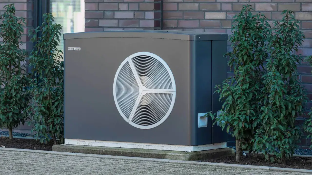 Nowoczesna pompa ciepła STIEBEL ELTRON. Jaka moc pompy ciepła do domu 200m2? Urządzenie stoi obok zielonych krzewów.