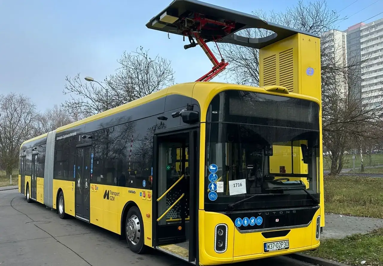 Żółty przegubowy autobus elektryczny z pantografem na dachu, symbolizujący elektromobilność w zamówieniach publicznych.