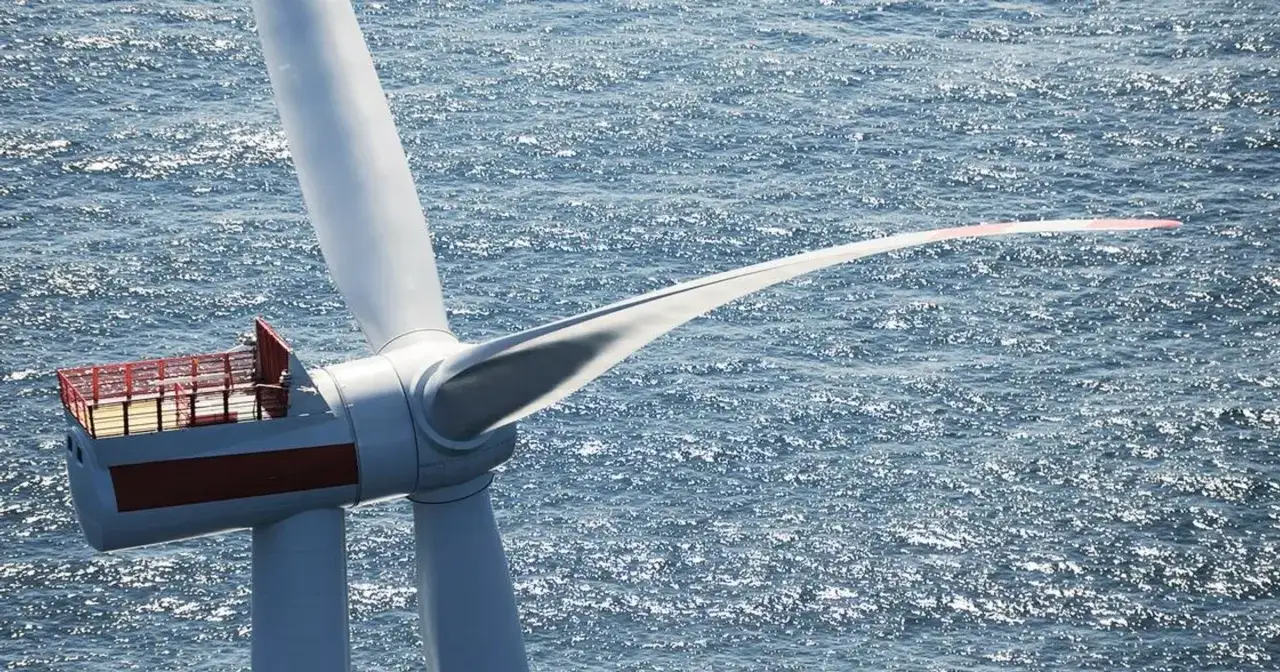 Turbina wiatrowa na morzu, element krajowego projektu energetycznego. Błękitna woda i białe łopaty tworzą obraz przyszłości.