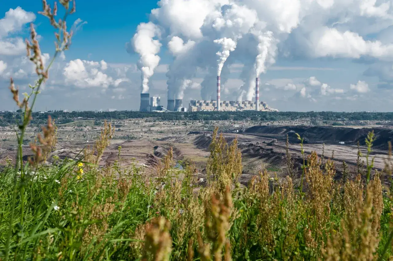 Widok na kopalnię odkrywkową i elektrownie węglowe w Polsce, z których unosi się dym.