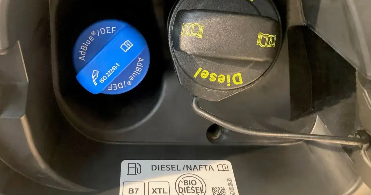 Dwa korki wlewu paliwa: jeden niebieski z napisem AdBlue/DEF, drugi czarny z napisem Diesel. Obok etykieta z oznaczeniem paliwa, w tym BIO DIESEL, czyli paliwo HVO.