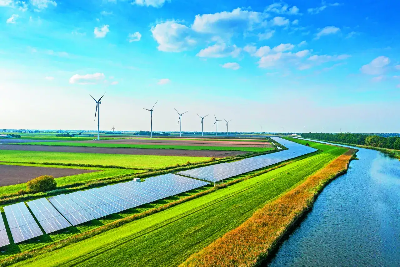 Wiatraki i panele słoneczne na tle pól i rzeki. To przyszłość polskich źródeł energii elektrycznej.